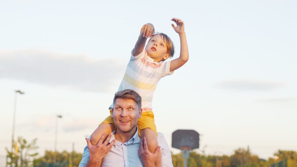 Son on father's shoulders outdoors